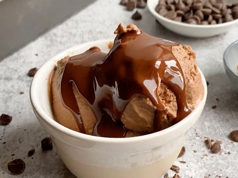 Chocolate ice cream drizzled with melted chocolate on a granite countertop