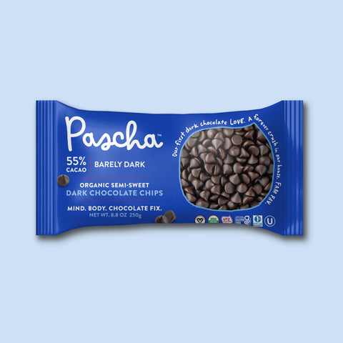 The front of the Pascha Chocolate 55% Barely Dark Organic Semi Sweet Baking Chips bag on a pink background