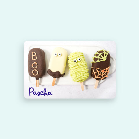 Four Halloween-themed fudgsicles on a white tray with 'Pascha' branding on a card.