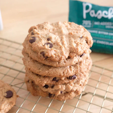 Stack of chocolate chip cookies resting on a cooling rack on a light brown counter top