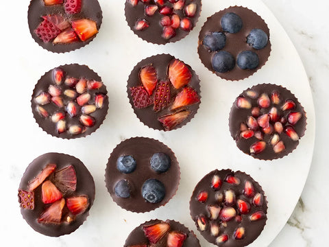 Chocolate fruit cups on a white tray on a marble counter
