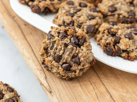 Stevia chocolate chip cookie leaning against white plate on wood board