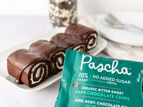 Pascha 70% Stevia chip bag beside swiss rolls coated in melted chocolate on a white plate