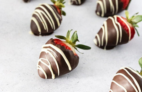 Chocolate covered strawberries laid on parchment paper and drizzled with white chocolate 