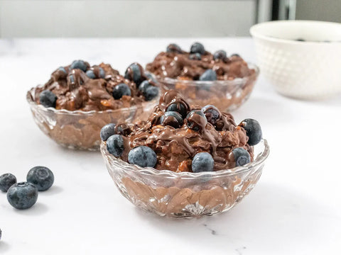 bowls of chocolate rice pudding topped with drizzled dark chocolate and blueberries