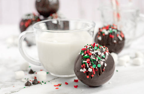 Vegan hot chocolate bombs next to a glass of milk.