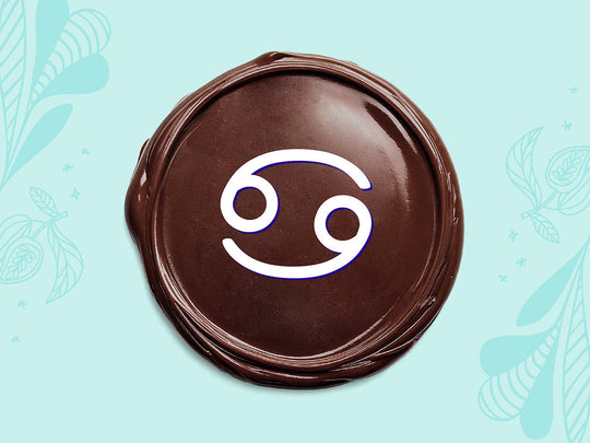 White Cancer sign on a disc of melted dark chocolate on a light teal background.