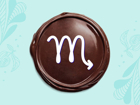 White Scorpio sign on a disc of melted dark chocolate on a light teal background.