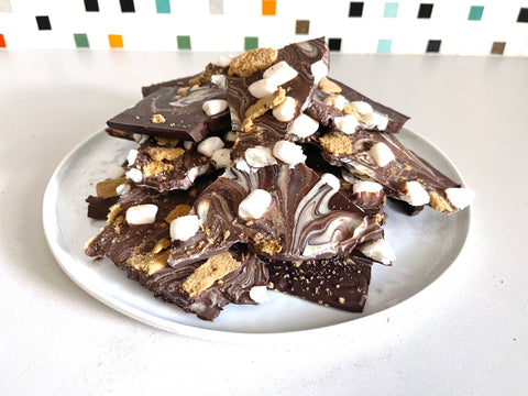Stack of chocolate bark with broken graham cracker pieces and mini marshmallows on a white plate