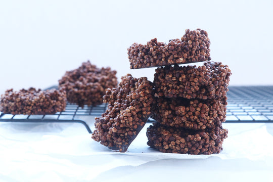 puffed quinoa chocolate cookies stacked four high with a fifth leaning on an angle against the stack with cooling rack and more in the background