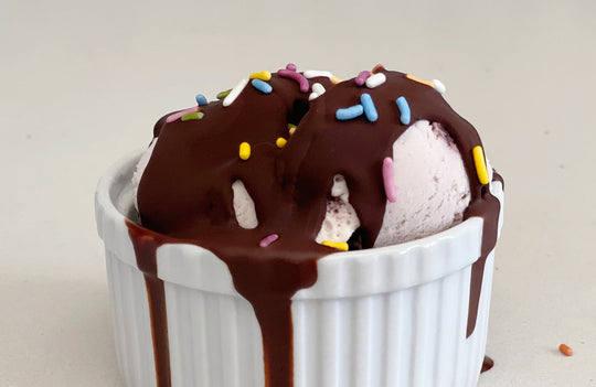 white ramekin filled with vanilla icing topped with dark chocolate magic shell and sprinkles