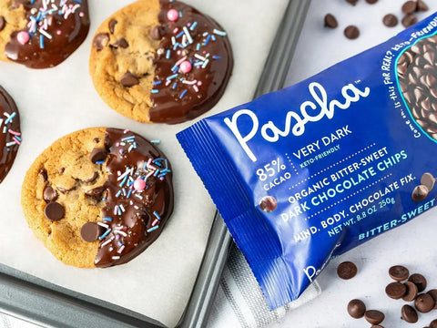 Pascha 85% chip bag beside a cookie tray with chocolate dipped chocolate chip cookies and sprinkles