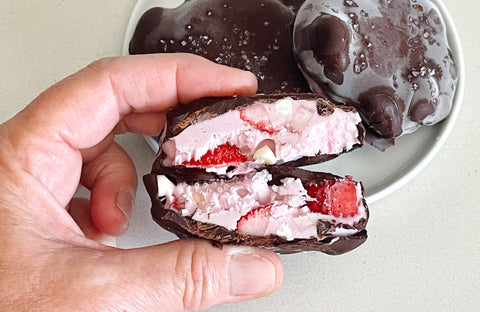 hand holding chocolate covered frozen strawberry yogurt treat