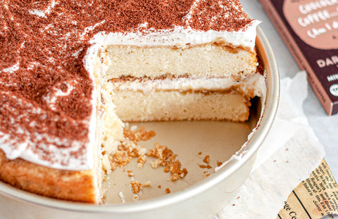 Round gluten free tiramisu cake with a slice cut out.