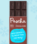 The front of Pascha Chocolate's 55% with Cocoa Nibs Dark Chocolate Bar with half of the exposed bar sticking out of the top of the packaging
