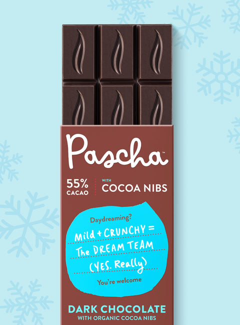 The front of Pascha Chocolate's 55% with Cocoa Nibs Dark Chocolate Bar with half of the exposed bar sticking out of the top of the packaging