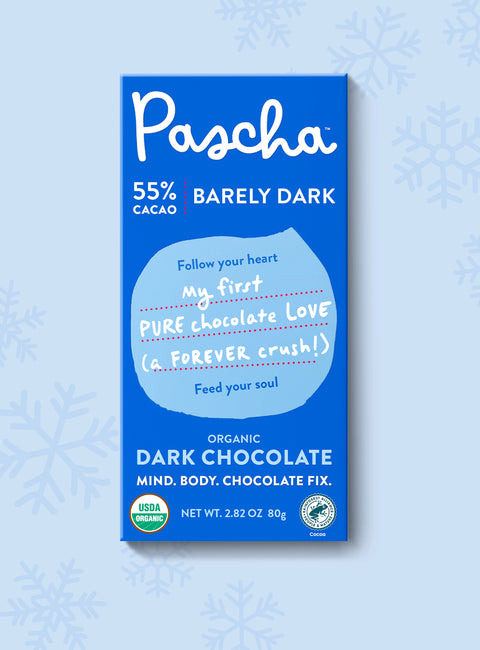 The front of Pascha Chocolate's 55% Barely Dark Chocolate Bar with half of the exposed bar sticking out of the top of the packaging