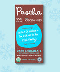 The front of Pascha Chocolate's 55% with Cocoa Nibs Dark Chocolate Bar with half of the exposed bar sticking out of the top of the packaging
