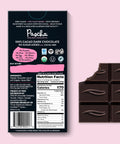 The back of Pascha chocolate's 100% cacao no sugar added with cocoa nibs dark chocolate bar and bar of chocolate with bite taken out of it.