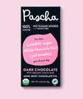 The front of Pascha Chocolate's 100% No Sugar Added with Cocoa Nibs Dark Chocolate Bar with half of the exposed bar sticking out of the top of the packaging
