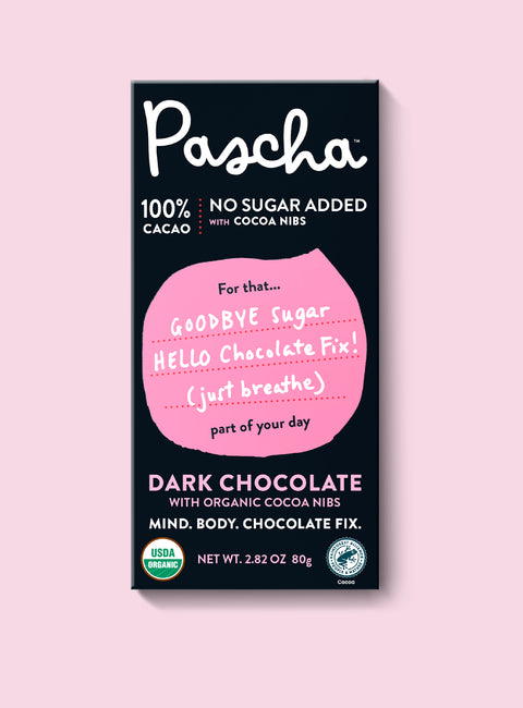 The front of Pascha Chocolate's 100% No Sugar Added with Cocoa Nibs Dark Chocolate Bar with half of the exposed bar sticking out of the top of the packaging