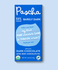 The front of Pascha Chocolate's 55% Barely Dark Chocolate Bar with half of the exposed bar sticking out of the top of the packaging