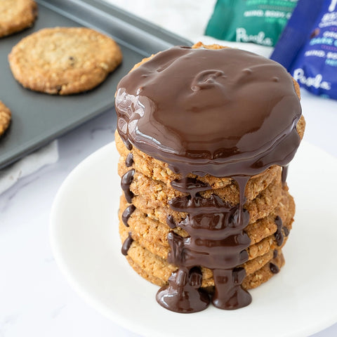 Stack of chocolate chip cookies with melted dark chocolate poured all over the top and down the sides.