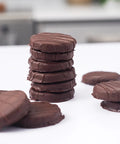 Stack of chocolate cookies on a white surface with a blurred background